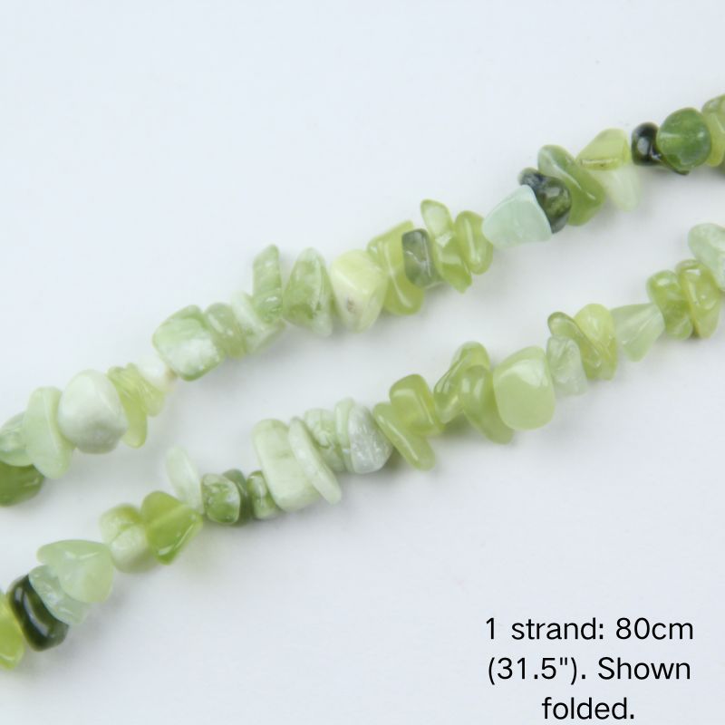 Close up of 5-8mm mixed green new jade stone chips with natural dark inclusions, strung on nylon cord