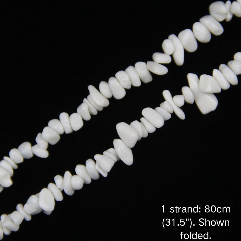 Macro close-up of white porcelain chip beads, 5-8mm smooth glossy ceramic finish.