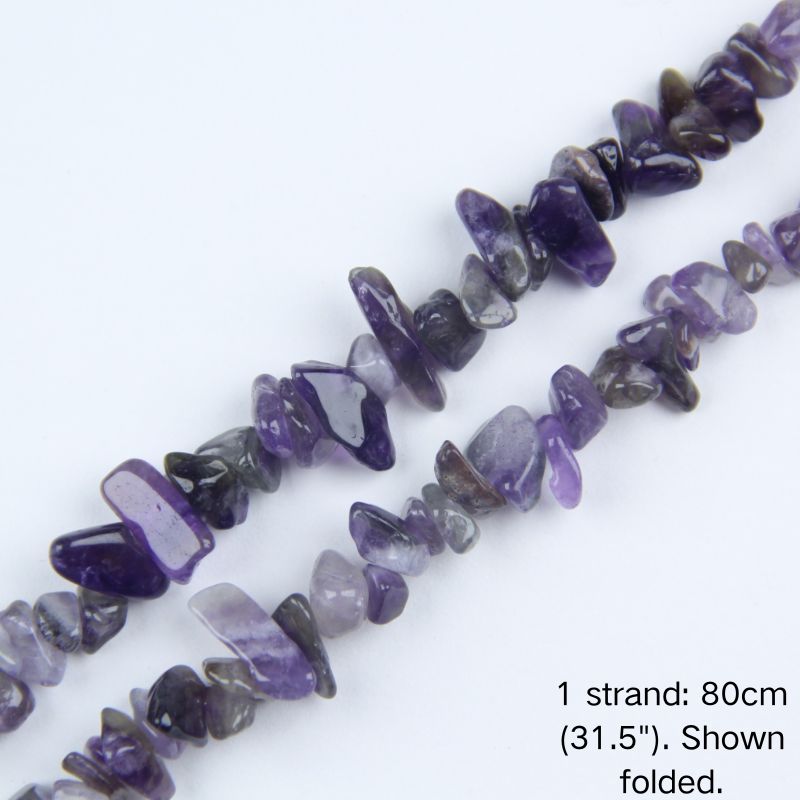 Macro close-up of glossy, translucent Amethyst irregular crystal chip beads, showing vibrant purple colors, polished texture, and center-drilled holes.