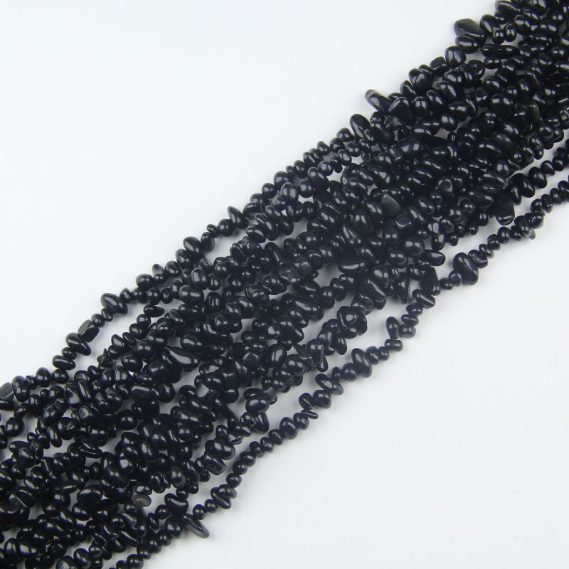 stack of black obsidian long bead necklaces displayed as collection on white surface