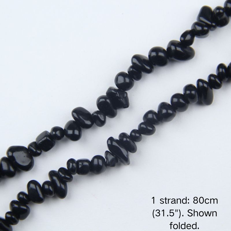Macro close-up of 5-8mm Black Obsidian chip beads, showing polished texture, glossy volcanic glass luster, and center-drilled holes.