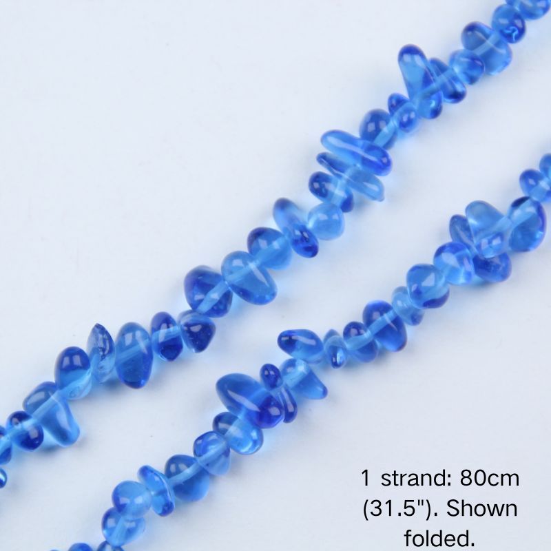 Macro close-up of glossy blue 5-8mm irregular glass chip beads, showcasing the polished texture, translucency, and center-drilled holes.