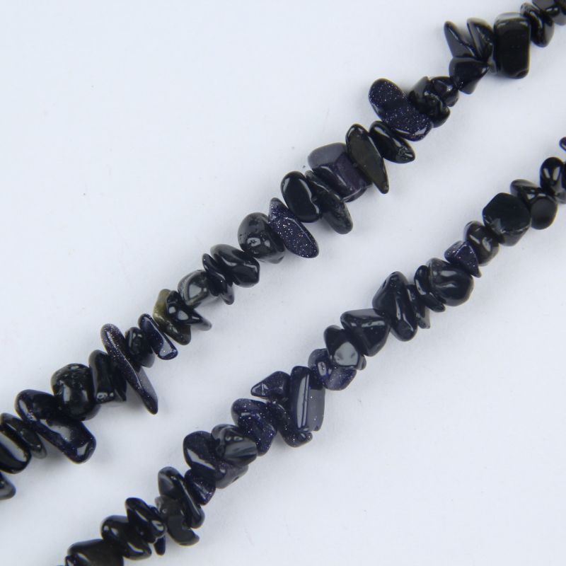 Close-up of blue sandstone beads showing tiny copper crystal sparkles suspended in deep midnight blue glass, glittering like a starry night sky