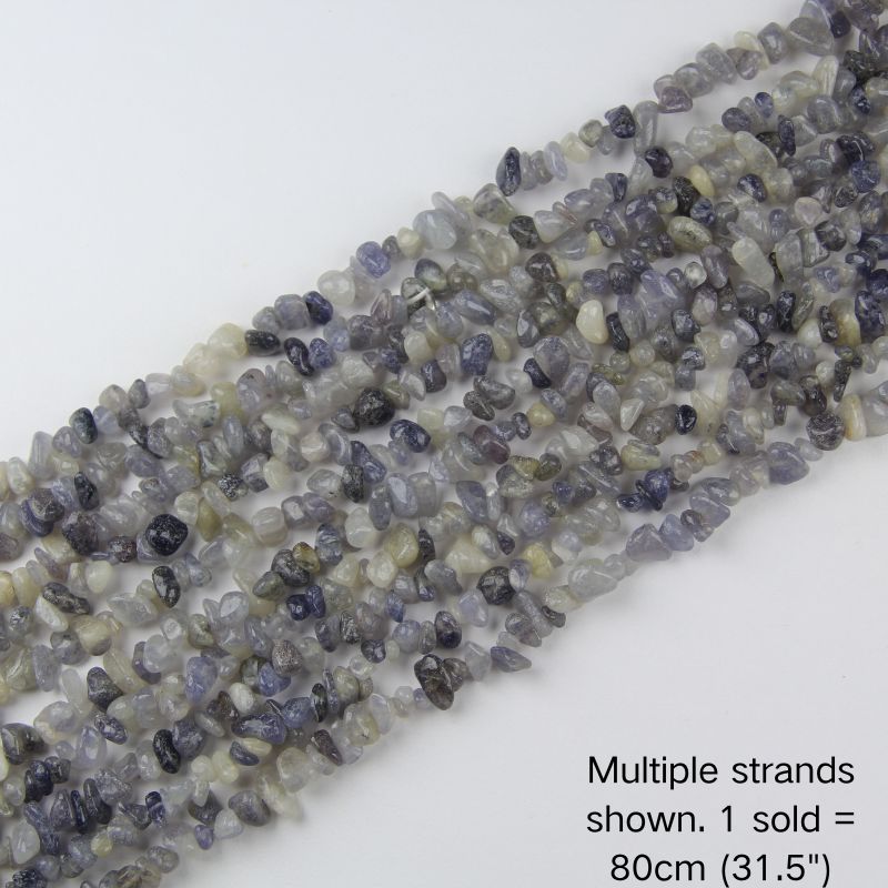 Multiple strands of natural 5-8mm Iolite chip beads laid out flat, showing the variety of colors and textures in bulk inventory