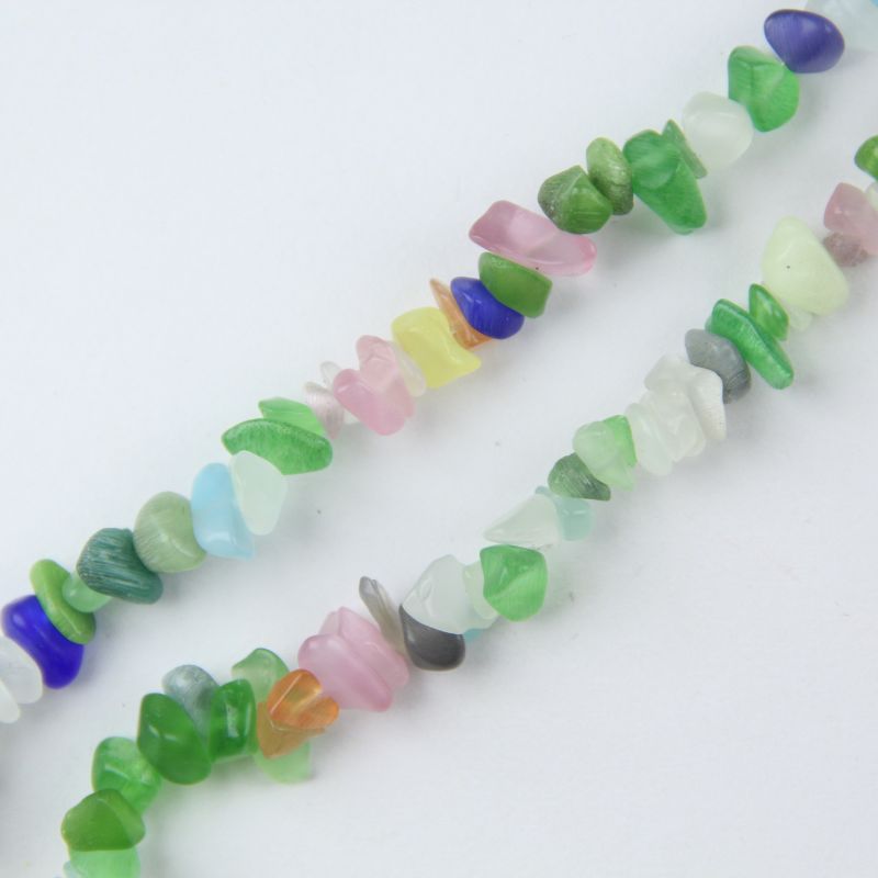 Close-up of cat's eye glass beads showing bright moving white light line through the center of each pastel pink, blue and green bead, fiber optic glow effect