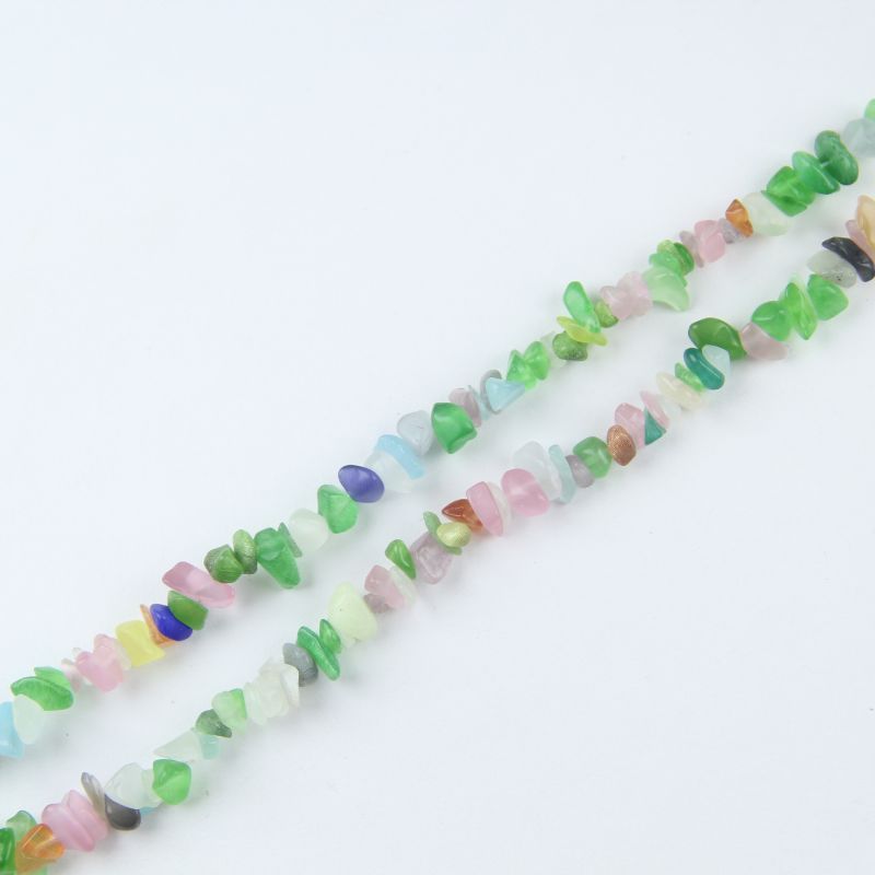 Single irregular cat's eye glass bead necklace laid flat on light surface, 31-inch strand with smooth polished rainbow beads