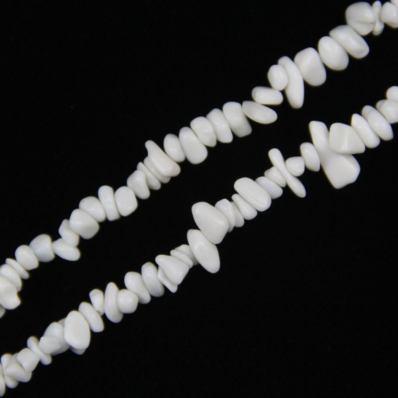 Close-up detail of irregular 5-8mm white porcelain beads showing smooth matte glaze and slight shape variations, plus the nylon cord end knot for durability.