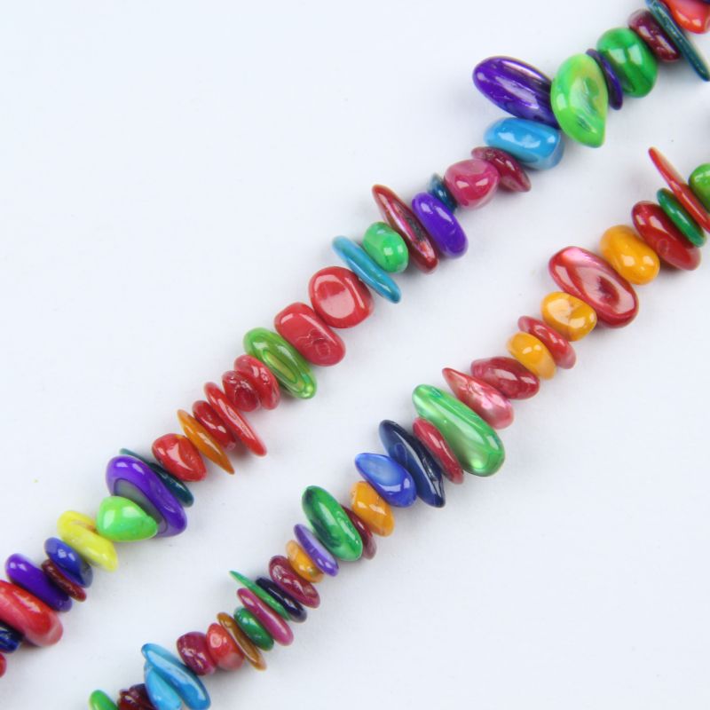 Close-up of dyed shell beads showing natural iridescent shimmer and matte-dyed color finish, pink and purple beads with shell texture visible