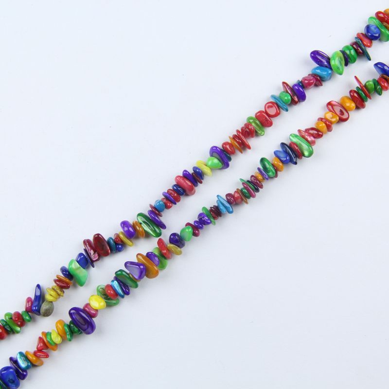 Single irregular colored shell bead necklace laid flat on light surface, 31-inch rainbow strand with freeform organic beads