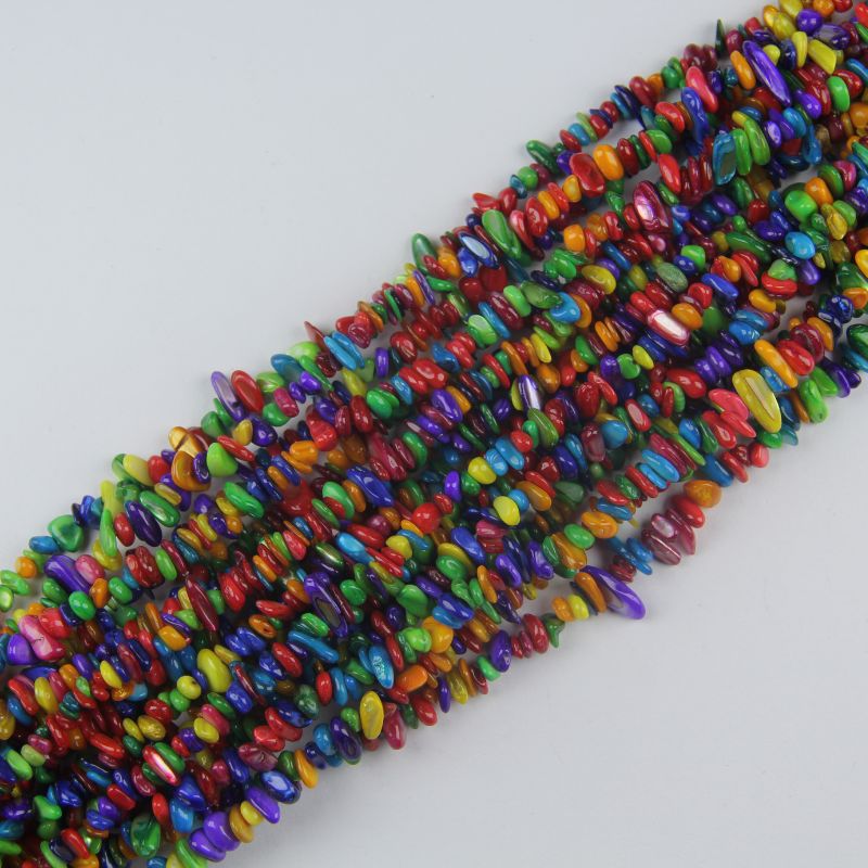 Multiple rainbow dyed shell long necklaces stacked together, showing full spectrum of colors from pink to purple