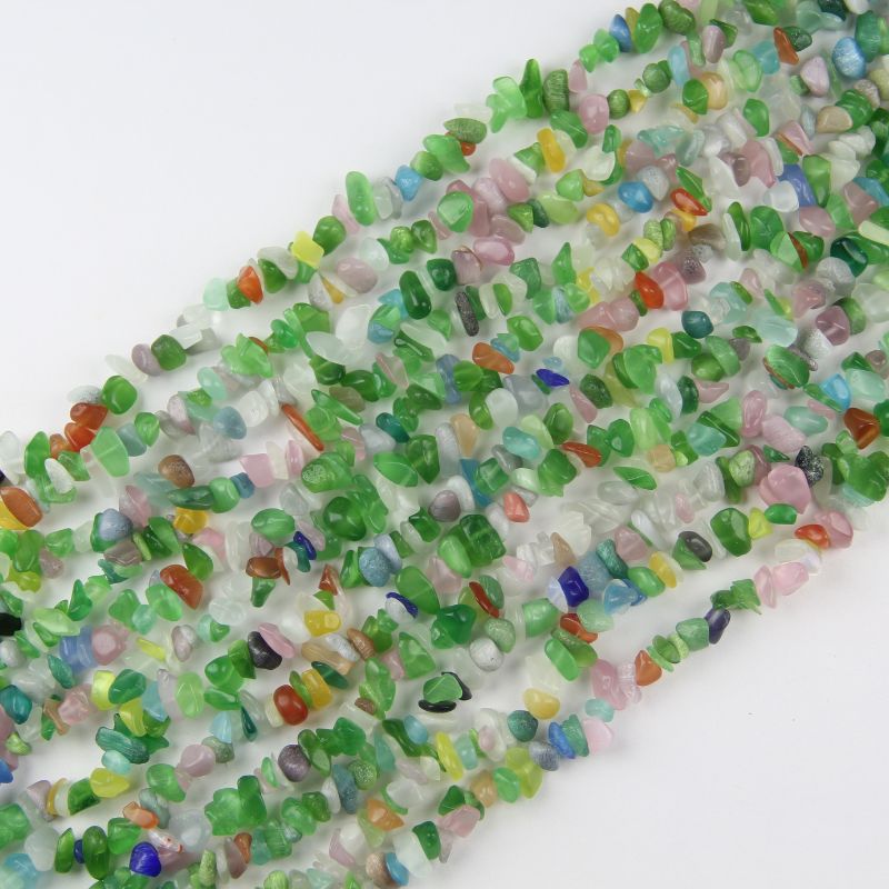 Irregular colorful cat's eye glass long necklace on white background, pastel rainbow beads in pink, blue, green, yellow, white and lavender with visible bright cat's eye light line on each bead