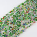 Irregular colorful cat's eye glass long necklace on white background, pastel rainbow beads in pink, blue, green, yellow, white and lavender with visible bright cat's eye light line on each bead