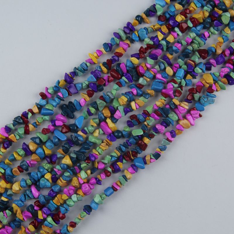 Irregular dyed howlite bead long necklace on white background, rainbow colored beads in turquoise, green, pink, purple, yellow and blue with natural black spiderweb matrix visible