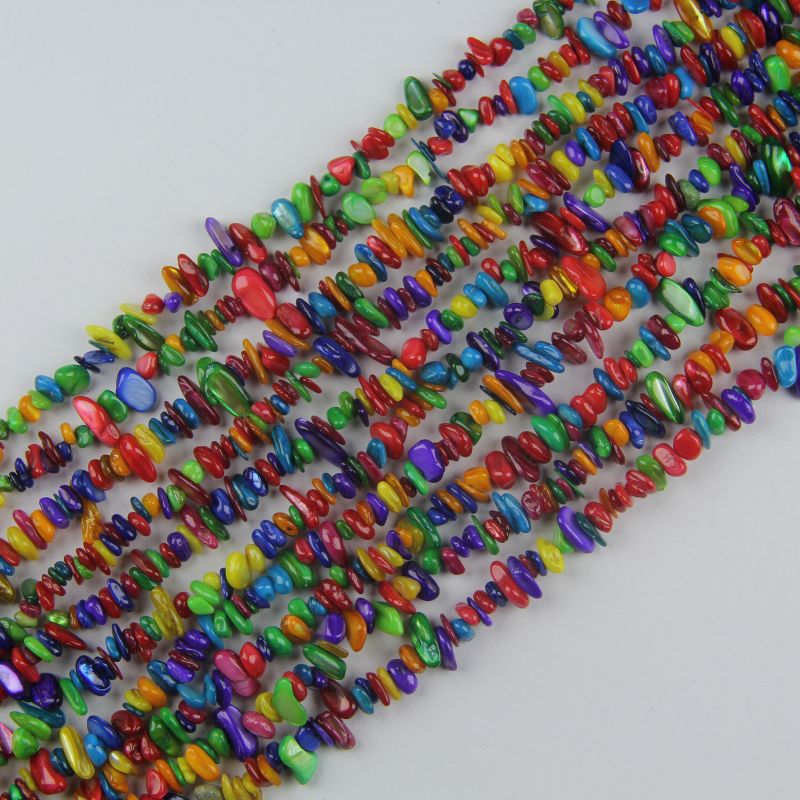 Irregular dyed shell bead long necklace on white background, rainbow colored beads in pink, coral, yellow, mint, blue, lavender and purple with natural iridescent luster
