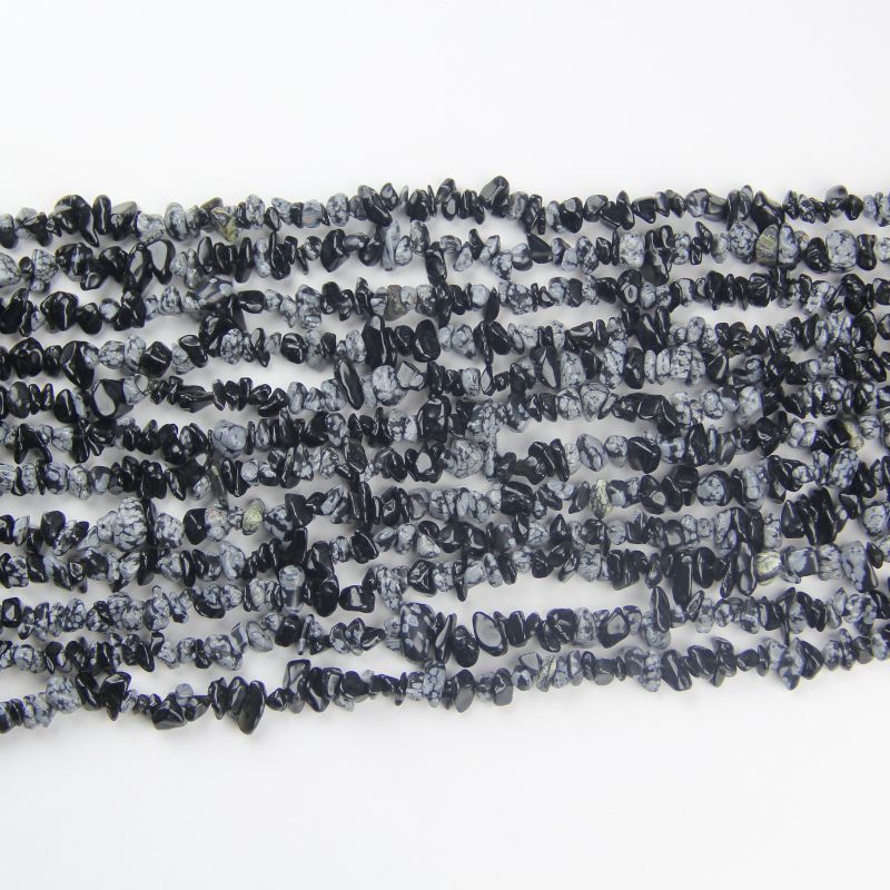 multiple snowflake obsidian long bead necklaces laid flat and stacked together on white background showing white snowflake patterns on each chain