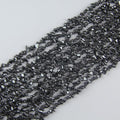 Natural iron stone chip bead strand 31.5 inches long on white background, gray-black 5-8mm irregular magnetic hematite chips with metallic luster strung on nylon cord