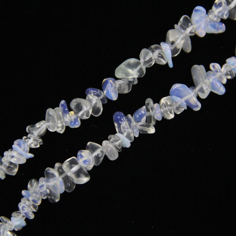 Opalite beads held against light showing warm peach and lavender undertones, soft opalescent sheen with rainbow hints in translucent glass