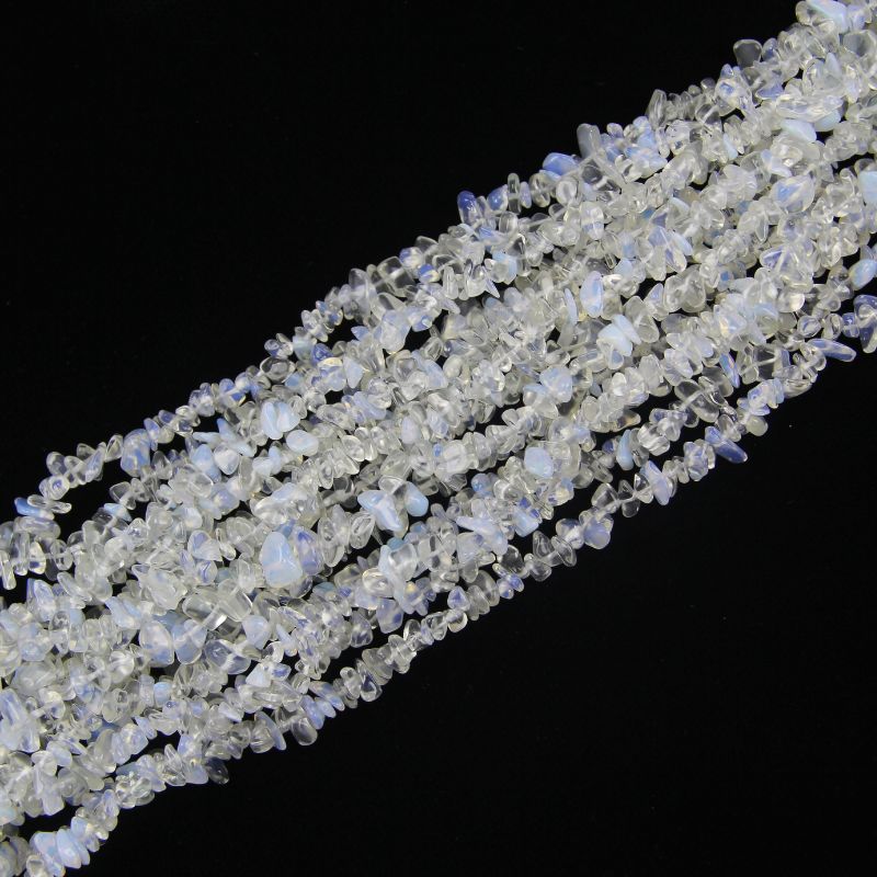 Multiple opalite long necklaces stacked together, showing milky white to pale blue colors and ethereal moonlit glow across all strands