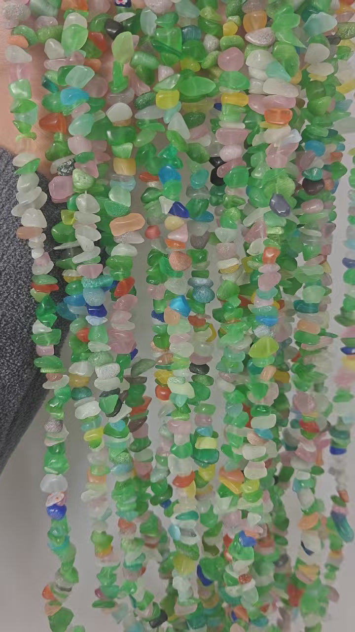 360 rotation of colorful cat's eye glass long necklace, bright light line moving across each pastel rainbow bead as the strand rotates