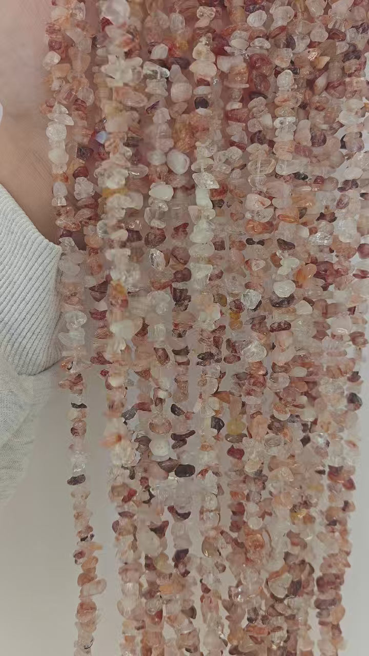 red floral inclusion quartz long bead chain lifted and released showing natural drape, gravity fall, and flower-like red inclusions catching light