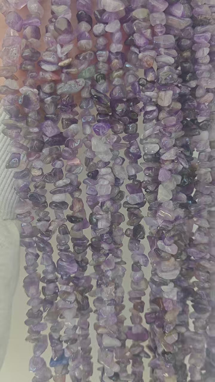 Video showing multiple strands of natural amethyst beads, each 31.5 inches long, featuring 5-8mm irregular round beads threaded on durable nylon cord. Strands are displayed hanging to showcase classic purple color, translucency, and length.