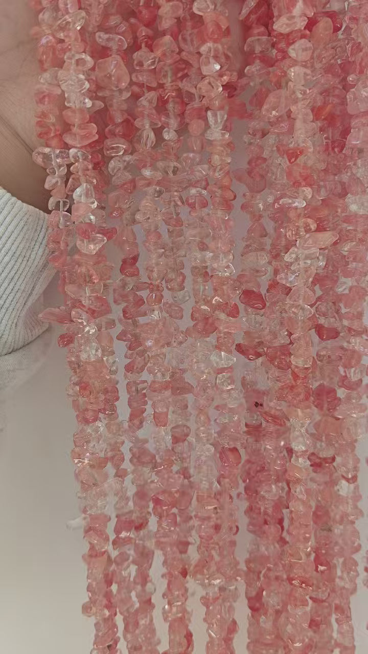 Video showing multiple strands of natural watermelon red crystal beads, each 31.5 inches long, featuring 5-8mm irregular round beads threaded on durable nylon cord. Strands are displayed hanging to showcase juicy pinkish-red color and natural variations.