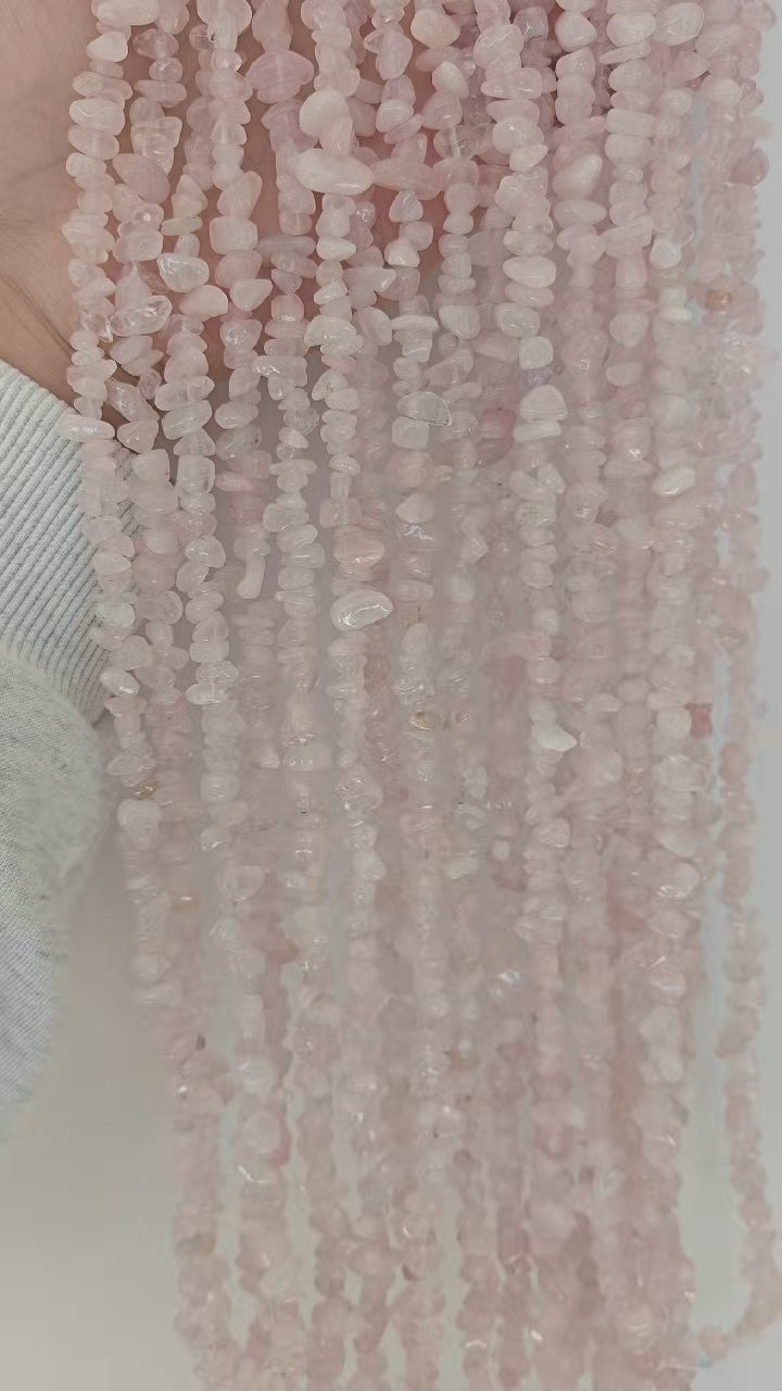 Video showing multiple strands of starry pink moissanite beads, each 31.5 inches long, featuring 5-8mm irregular round beads threaded on durable nylon cord. Strands are displayed under light to showcase intense rainbow fire and soft pink blush.