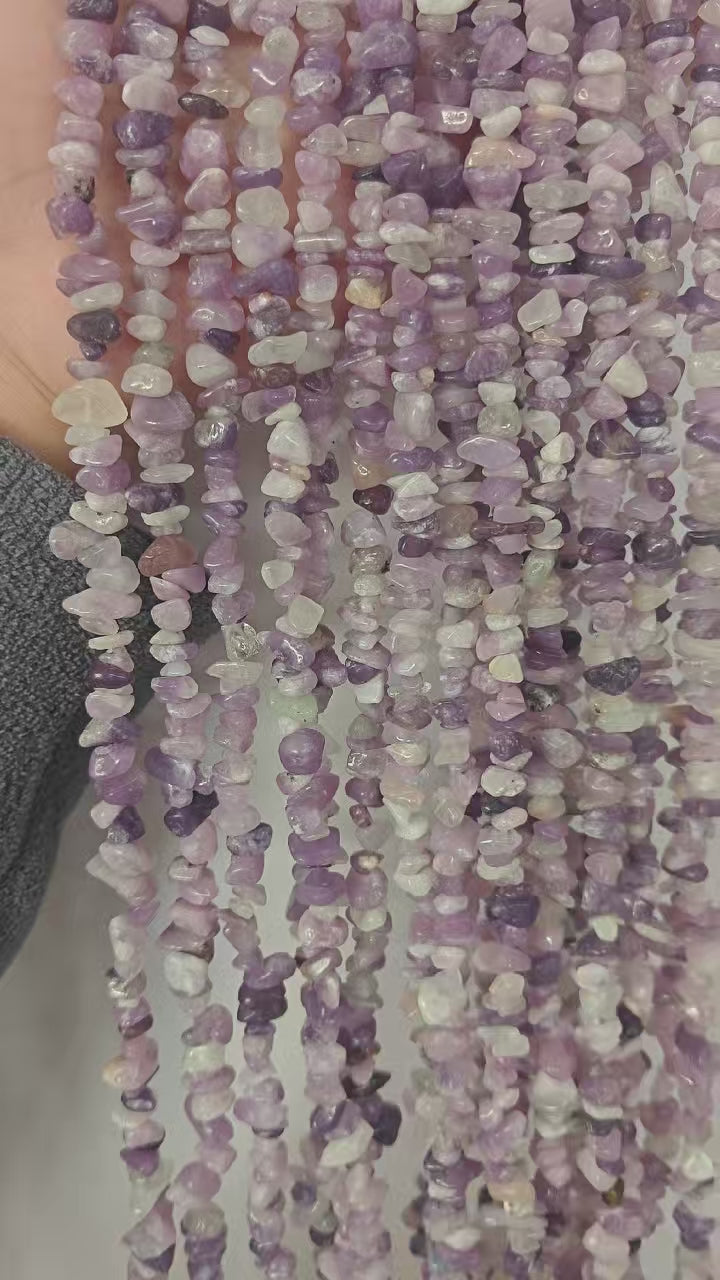 Video showing multiple strands of natural lilac crystal beads, each 31.5 inches long, featuring 5-8mm irregular round beads threaded on durable nylon cord. Strands are displayed hanging to showcase delicate pale purple color and gentle translucency.