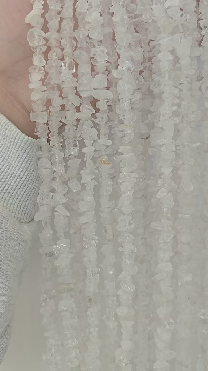 Video showing multiple strands of natural white cotton crystal beads, each 31.5 inches long, featuring 5-8mm irregular round beads threaded on durable nylon cord. Strands are displayed hanging and side-by-side to highlight length, soft white color, and natural cotton-like inclusions.