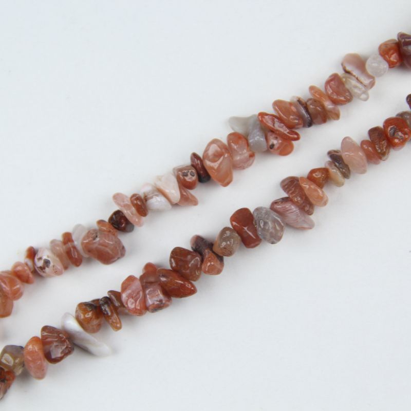 Close-up of natural red agate beads, showing deep red color, subtle banding, and slight surface variation