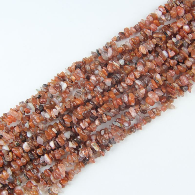 Multiple red agate long necklaces stacked together, showing rich red hues and slight color variation between strands