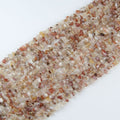 Red and white agate irregular bead long necklace on white background, natural red and cream banding visible on each freeform bead