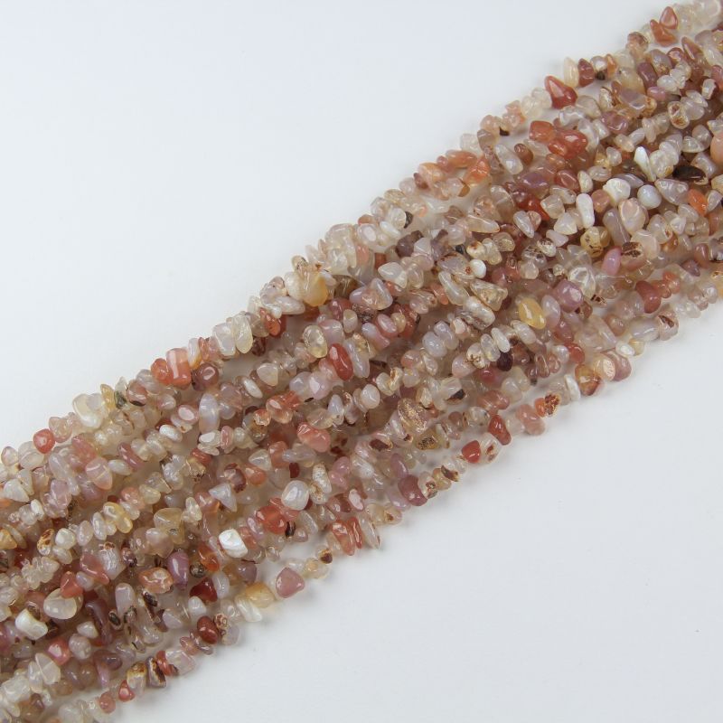 Multiple red and white agate long necklaces stacked together, showing variation in red and cream banding patterns