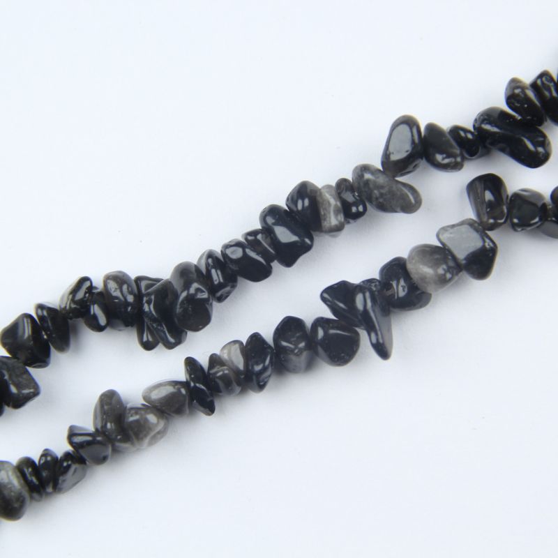 closeup of silver obsidian bead showing metallic silver shimmer and reflection on black volcanic glass surface