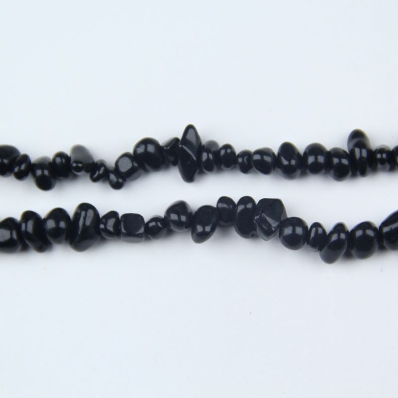 macro closeup of single black obsidian bead raw stone texture matte and uneven surface