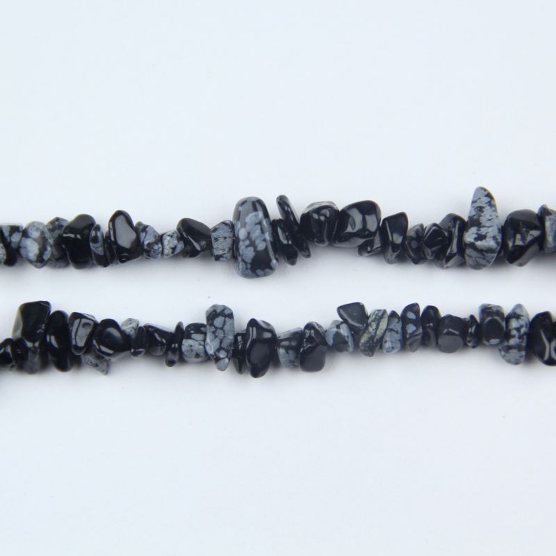 closeup of irregular snowflake obsidian beads lined up showing 5 to 8mm size variation and unique patterns