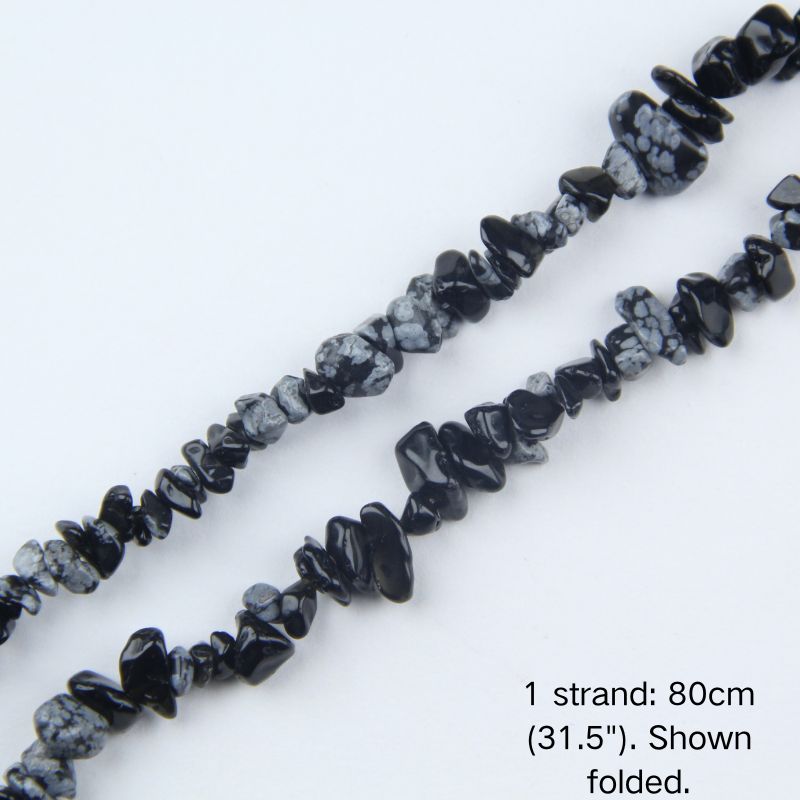 Macro close-up of 5-8mm Snowflake Obsidian chip beads, showing glossy volcanic glass surface, white snowflake inclusions, and center-drilled holes.