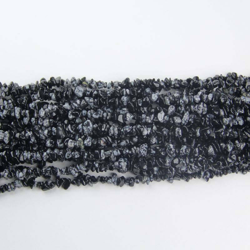 	stack of snowflake obsidian long bead necklaces laid flat showing white snowflake patterns on multiple chains