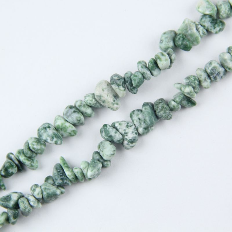 Close-up of tree agate beads, showing intricate black and green dendritic inclusions like miniature forests inside milky white agate