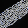 Irregular white blue opalite long necklace on white background, milky translucent glass beads with soft opalescent glow from white to pale blue