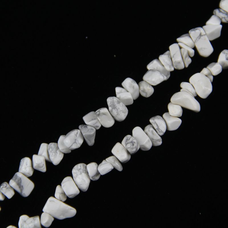 close-up of white howlite irregular round beads showing creamy white color and natural grey veining with nylon cord stringing, 5-8mm size